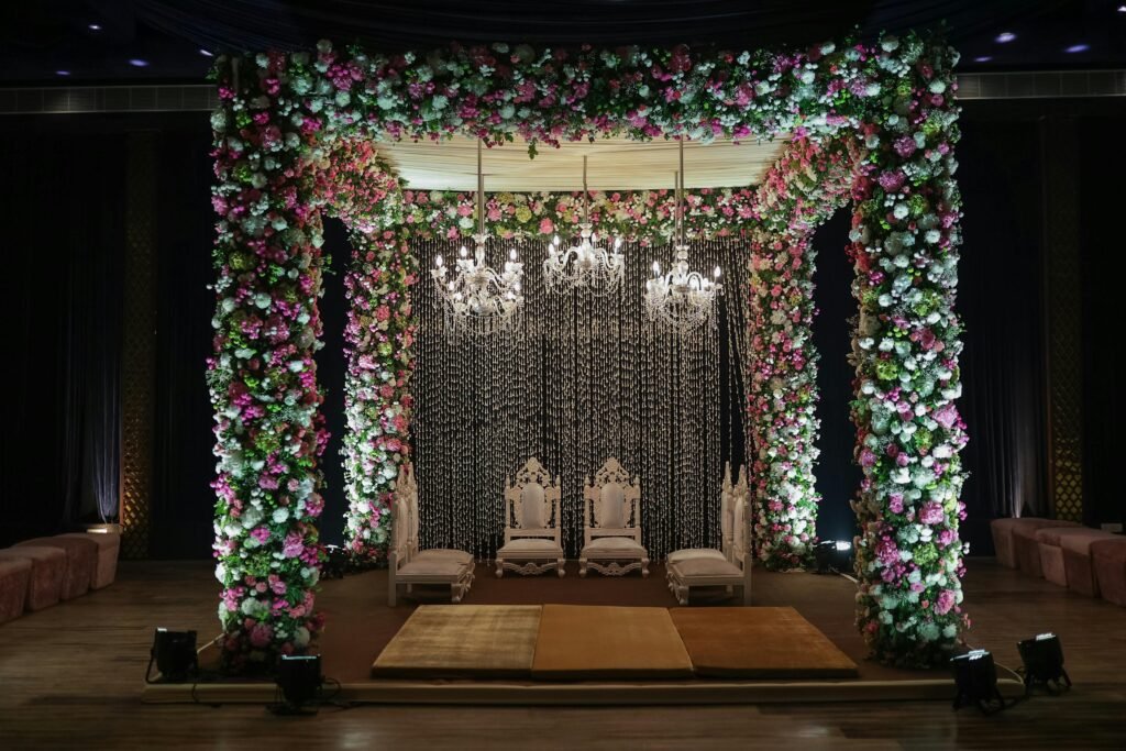 Luxurious floral wedding mandap decorated with chandeliers, perfect for elegant indoor ceremonies.